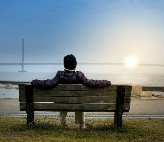 여름철 일사병 예방법 person sitting on bench facing suspension bridge