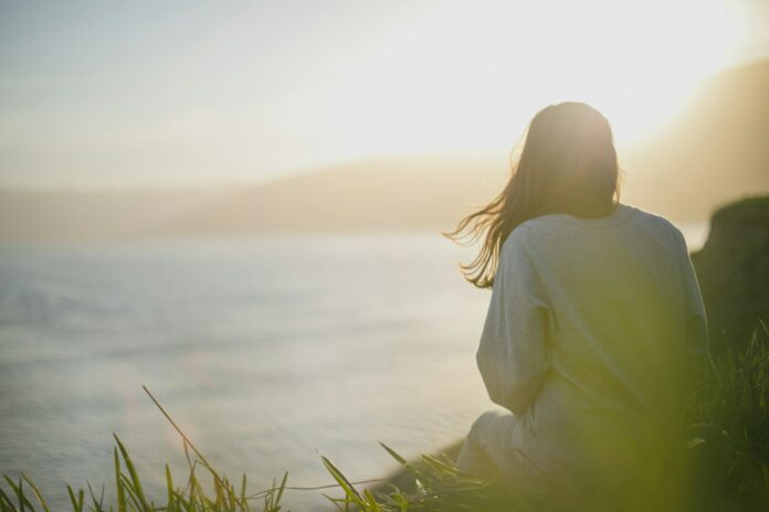 Photo by Artem Kovalev woman wearing gray long-sleeved shirt facing the sea