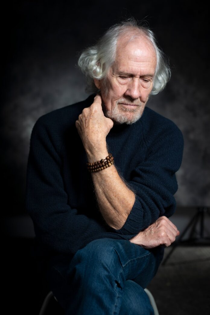 Photo by Jonathan Cosens Photography man in black long sleeve shirt sitting on chair