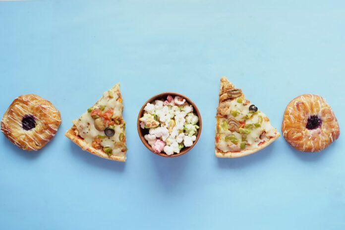 Photo by Towfiqu barbhuiya a bowl of popcorn and a slice of pizza on a blue background