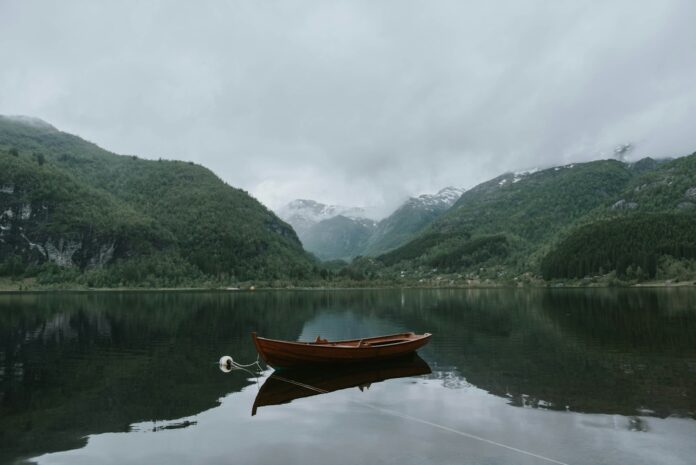 Photo by Wes Grant brown boat on body of water near green mountains under white sky at daytime