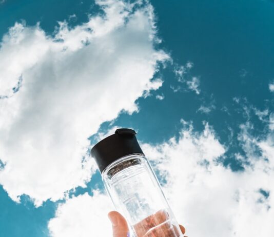 여름철 건강관리, 시원하고 안전하게 보내는 법 a hand holding a water bottle in front of a blue sky