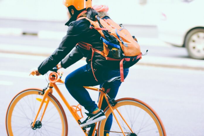 Photo by Jackie Alexander closeup photo of person riding a orange bicycle