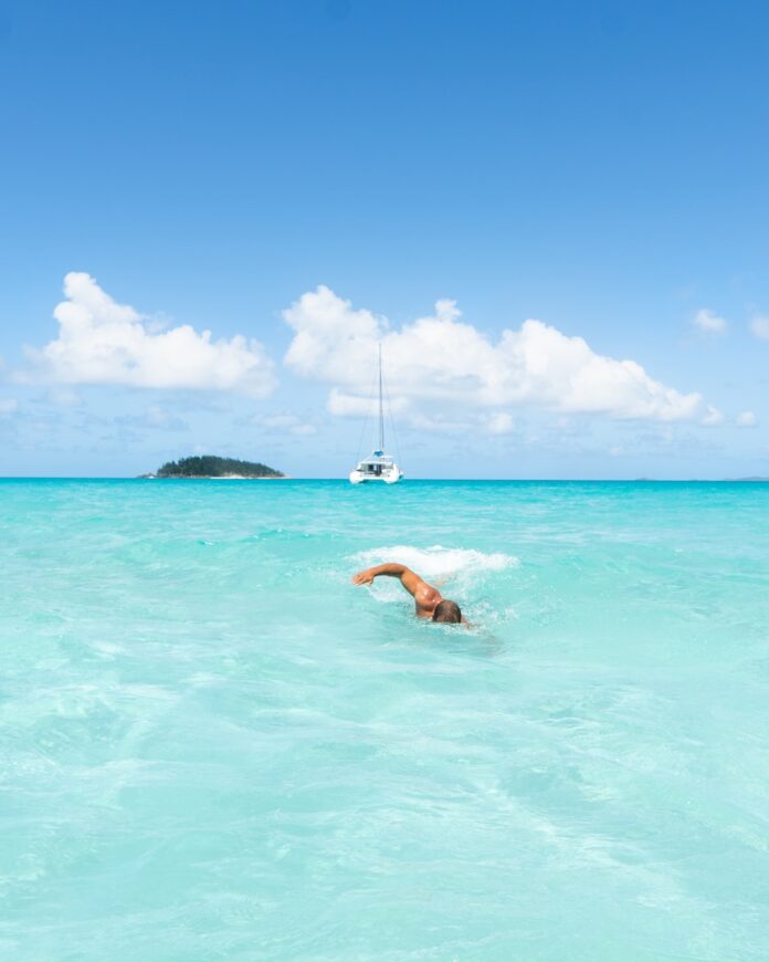 Photo by Calvin Shelwell woman in blue bikini swimming on sea during daytime